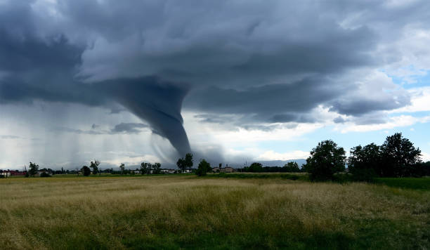 Rural landscape with hay bales, tornado in background, dramatic scene